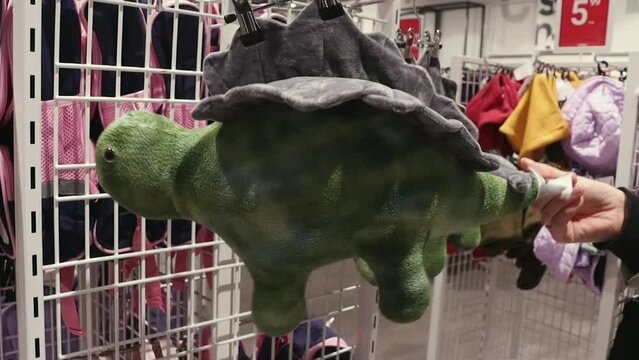 Children's soft toy dinosaur in the store. A customer touches a children's soft dinosaur toy in a store.
