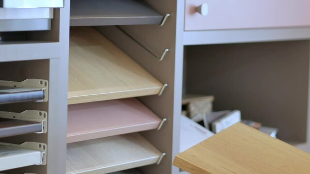 Women's hands take out of the closet a sample of laminated chipboard decor in the store external color palette and textures. The choice of material for new furniture.