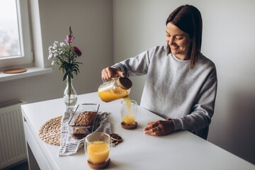 A beautiful woman with vitiligo with bob pours sea buckthorn tea and is going to have breakfast with homemade fresh banana muffin with berries. Concept of healthy breakfasts  - obrazy, fototapety, plakaty