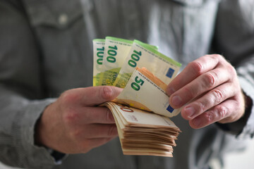 
a man holds euro money in his hand and counts them. close-up view on a blurred background