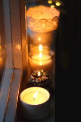 Lit candles and Christmas decorations on the window sill at night. Hygge at home. Selective focus.