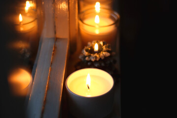 Lit candles and Christmas decorations on the window sill at night. Hygge at home. Selective focus.