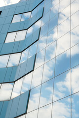 modern facade of glass and steel with reflections. Abstract or graphic photo of the sky with clouds seeming to continue into a building with reflective squares of glass