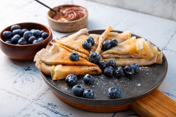 Thin pancakes with chocolate spread and blueberries on the table