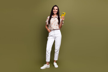 Full length photo of mature smiling beautiful business lady hold smartphone working remote influencer isolated on khaki color background