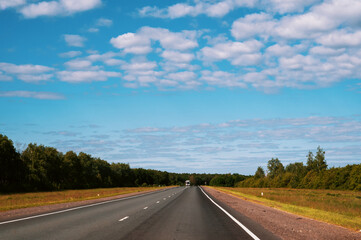highway going into the distance. Gorgeous view of highway going into distance through forests against background of blue sky with white clouds