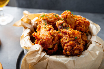 Bowl of deep fried chicken wings with bbq souse and beer on gray table close up