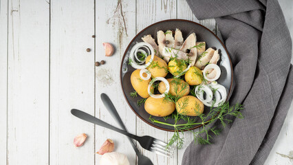Traditional scandinavian food: salted herring slices with boiled potatoes and fresh raw onions. ...