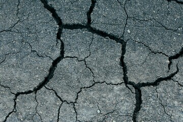 cracked pavement with the cracked ground visible through it's crack