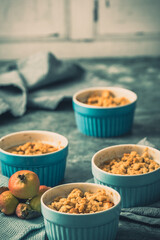 Apple crumble in small blue molds on a rustic gray table