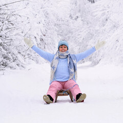 Fototapeta na wymiar lachende Frau auf einem Schlitten im Winterwald