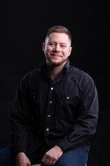 Strict and stylish Man in black shirt on dark background.