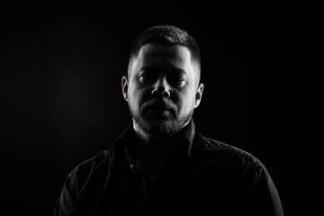 Strict and stylish Man in black shirt on dark background.
