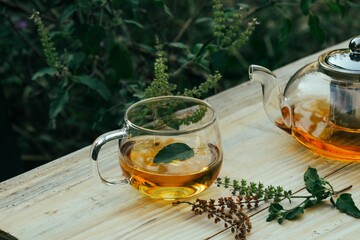 Glass teapot and mug filled with freshly brewed herbal basil tea.