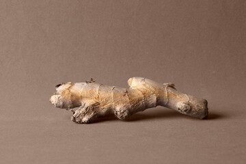 Photo of a piece of raw ginger on brown background