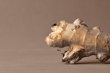 Photo of a piece of raw ginger on brown background