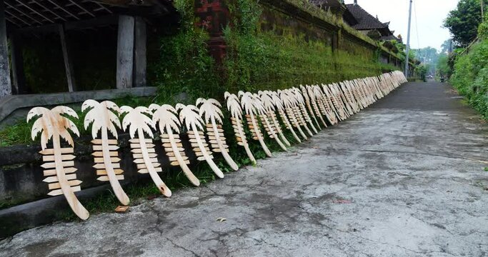 Wooden blanks for signs or ornaments in form of palm trees with arrow slats, drying outside house on street. Various types of crafts, from highly artistic to rather simple, are made by Balinese