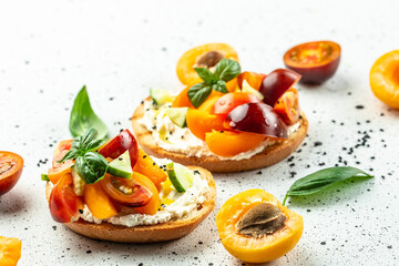 Toast, snack, bruschetta, sandwich with cream cheese, peaches, tomatoes and green basil leaves, Concept healthy and balanced eating. place for text, top view
