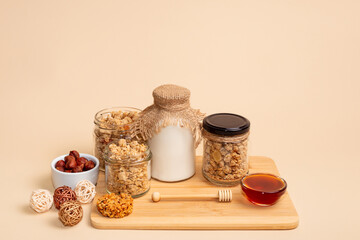 Healthy breakfast cereal. Granola with milk, glass of milk, honey, nuts and muesli cookie on light...
