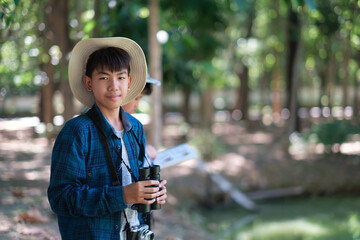 Kid exploring the forest hiking and camping, scouting, learning about the wildlife, using a binocular to search for animals with friends. Happy smiling excited summer vacation.
