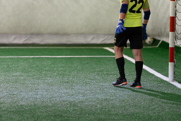 Futsal goalkeeper during the game. Indoor artificial grass five-a-side soccer match.