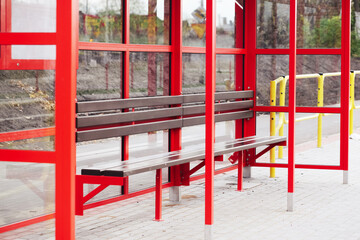 Fototapeta na wymiar Brand new bus stop. Bialystok city in Poland, Europe. New road construction. Red paint steel bus stop construction with wooden bench. Public transport background.