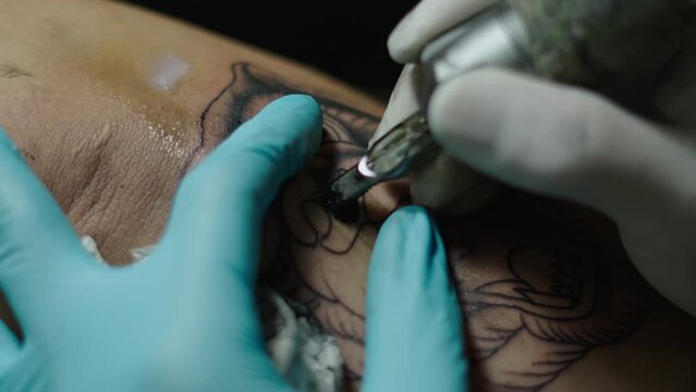 macro shot of a tattoo machine tattoing in skin