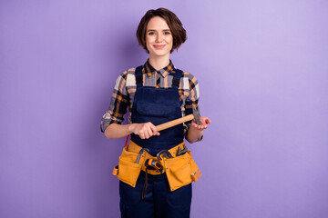 Photo of young woman builder craftsman hold hammer tools repair restoration isolated over violet color background - obrazy, fototapety, plakaty