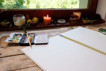 A watercolor workbook, brushes and paints - the artist's workplace near the window