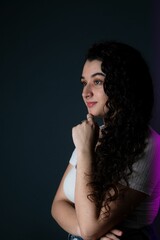 Young woman is looking away from the camera, her hands resting beneath her chin