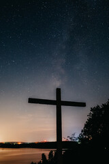 Cross overseeing lake on a starry night
