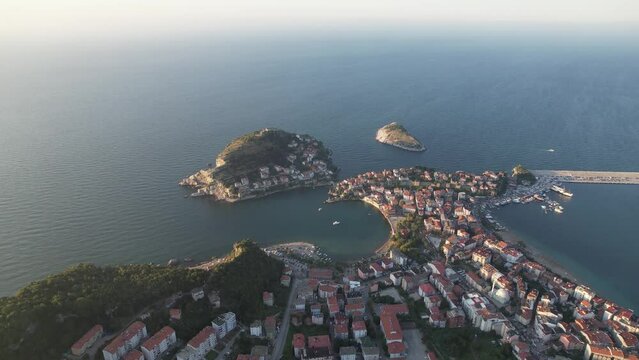 City view in the Amasra mountains. The drone is slowly approaching the beautiful landscape. Aerial view of houses and deep blue sea. Amasra, Turkey.