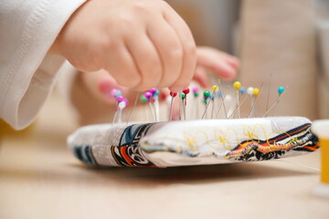 The child takes sewing needles with his small fingers.