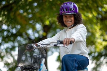 Fototapeta na wymiar Smiling dark-skinned girl on a bike in a park