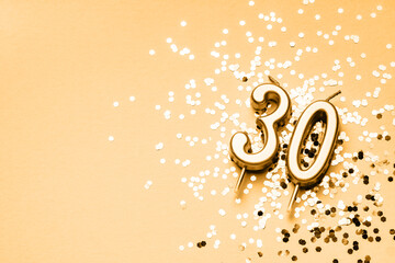 30 years celebration festive background made with golden candles in the form of number Thirty lying on sparkles. Universal holiday banner with copy space.