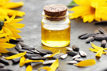 Sunflower oil with fresh flowers, seeds, petals on black table, closeup, copy space, cooking...