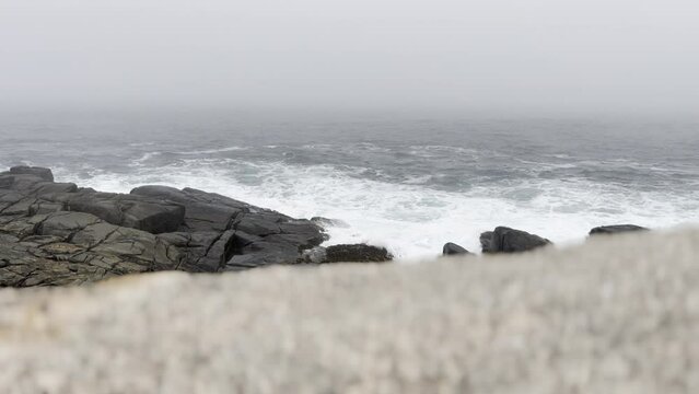Selective focus view of foamy waves crashing on a rocky coastline