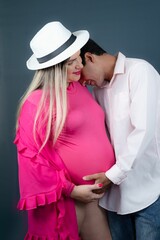 Loving couple, both with visible baby bumps, embrace each other against a dark blue background