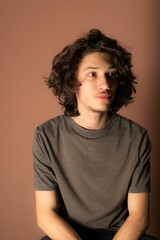Caucasian young man sitting against a beige background
