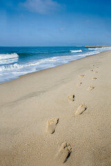 Footprints in the sand with Pacific Ocean 