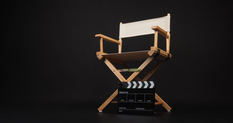 Clapper board with white director chair on black background.