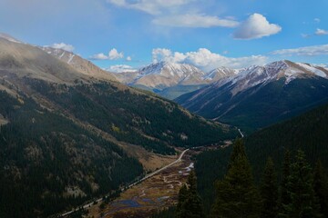 Fototapeta premium Scenic view of rolling hills and lush evergreen trees with wispy clouds in the sky