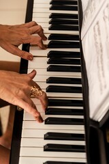 Female musician seated at a grand piano playing a melodic tune, with sheet music in view behind her