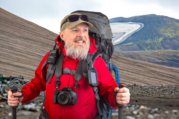 happy bearded man traveler with hiking equipment against the backdrop of a mountain landscape. travel, hiking and adventure