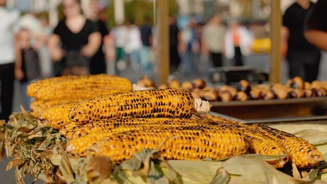 Famous Cheapest Turkish Street Food. Grilled corn and roasted chestnuts in cart in Istanbul. Closeup. Seller frying and selling in bag in tourist place.