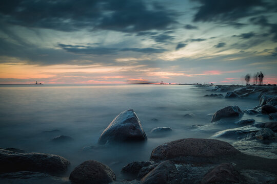 Long exposure image of dramatic sky seascape with rock in sunset scenery background