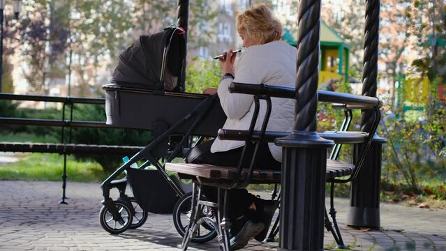 Grandmother on a walk with her grandson or granddaughter in a stroller on a nice warm day