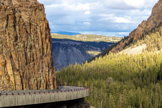 grand loop road at golden gate entering kingman pass in yellowstone national park, image shows the road curving round and descending along the cliff face with the forest background, october 2023