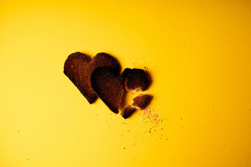 Broken hearted. Two burnt hearts made of white toast bread on yellow background. Conceptual...