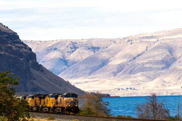 Pacific coast locomotive can be seen using the railway parallel with the Columbia river and highway 84 with a beautiful scenic background and the river  
